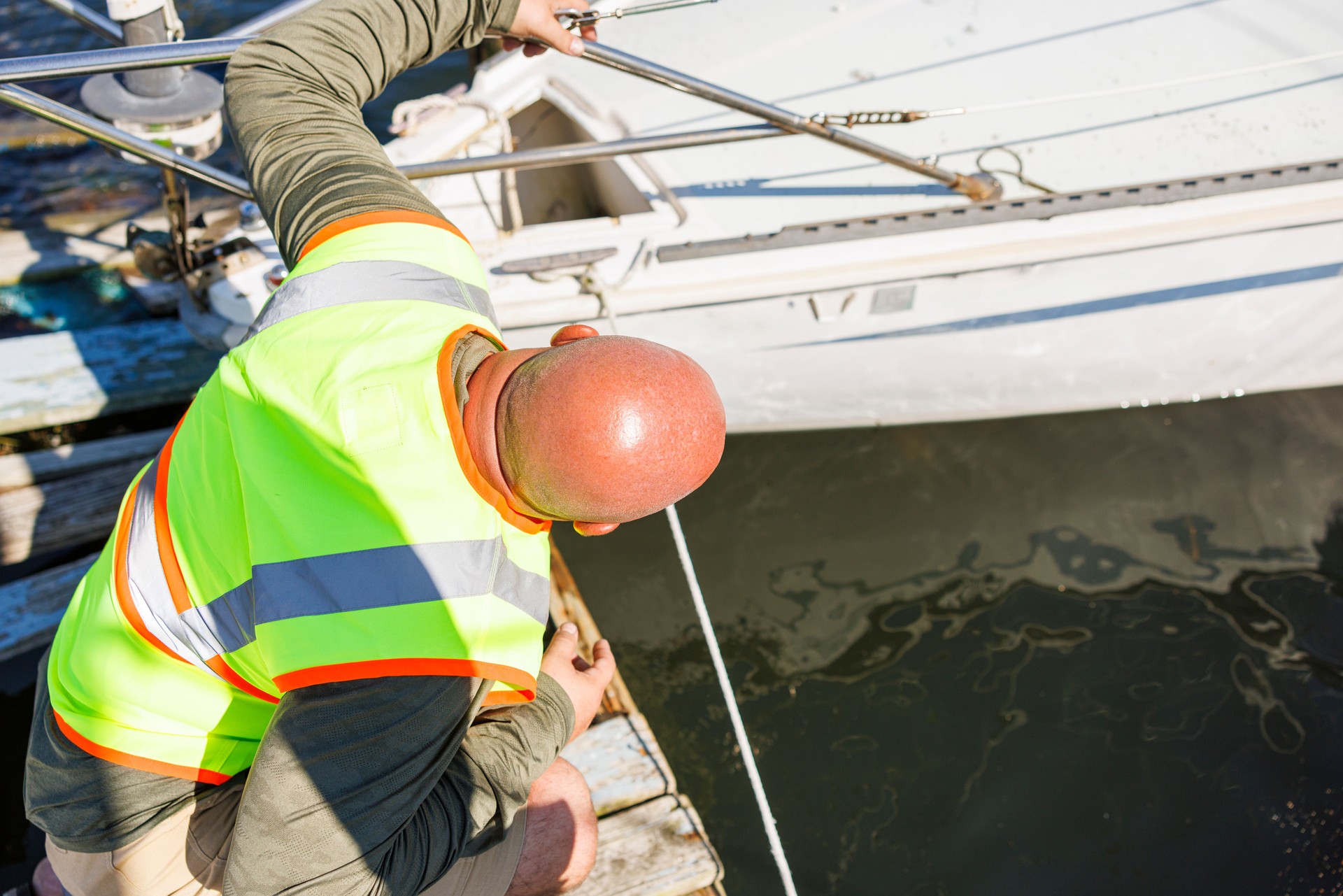 Security and control inspection of a drowned yacht. Mature bald repairman inspecting and estimating repair for yacht damaged by storm. Top view